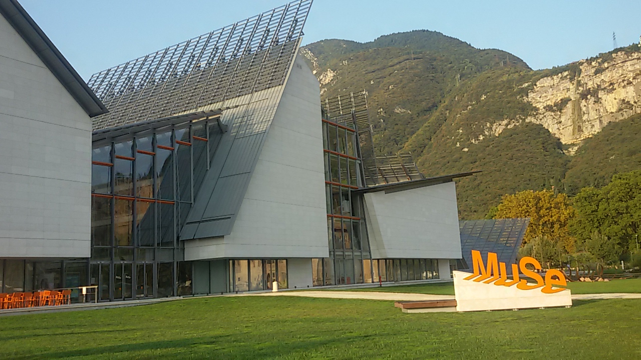 MUSE-Gebäude in Trient mit orangefarbenem Schriftzug und Bergen im Hintergrund